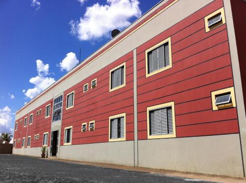 um edifício vermelho e branco com janelas em Apart Cavalari Kitnets em Marília