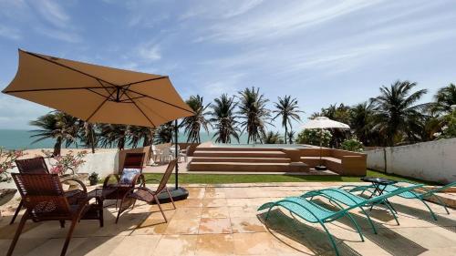 eine Terrasse mit Tisch und Stühlen und einem Sonnenschirm in der Unterkunft Vista pro mar maravilhosa,Tibau-RN - INNOVA in Tibau