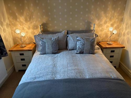 a bedroom with a blue bed with two night stands at Hatters Cottage in Bingley