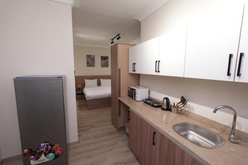 eine Küche mit Spüle und weißen Schränken und ein Schlafzimmer in der Unterkunft Settle Inn Banafseg Apartments in Kairo