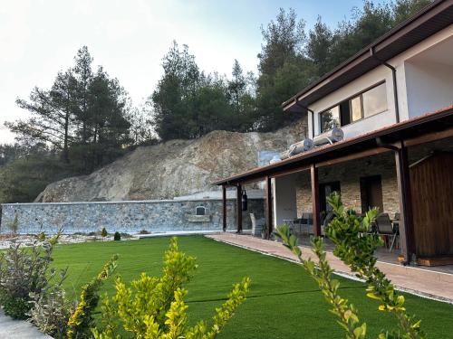 una casa con un cortile con erba verde di ANTHEMIs COTTAGE RED a Kyperounda