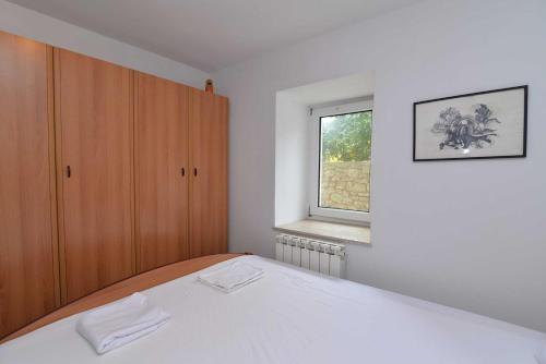 a bedroom with a white bed and a window at Studio Veli A in Veli Lošinj