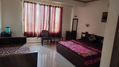 a bedroom with a bed and a window with red curtains at Hiral residency in Matheran