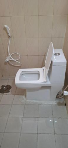 a white toilet in a bathroom with a hose at Ashwin Home Stay in Tiruvannāmalai