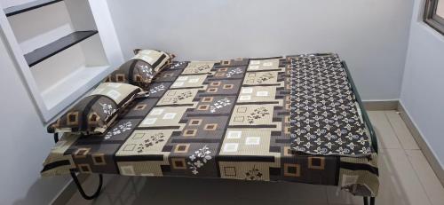 a bed with a quilt on it in a room at Ashwin Home Stay in Tiruvannāmalai
