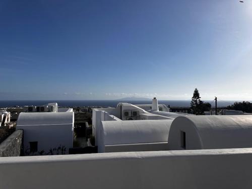 eine Gruppe weißer Gebäude mit dem Ozean im Hintergrund in der Unterkunft Erthā Suites with private pools in Vóthon