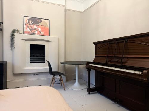 a bedroom with a piano and a table at Stylish, Spacious City Hideaway - Sleeps up to 9 in Cardiff
