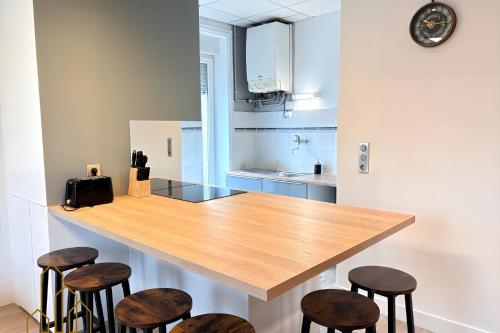 una cucina con bancone in legno e sgabelli di Le Dourdein - Chic & Confort a Roanne