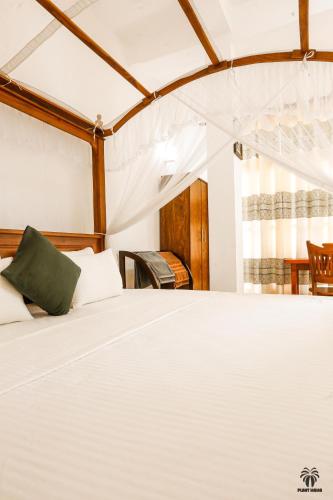 a bedroom with a white bed with a green pillow at Plant Mama Guest House in Weligama