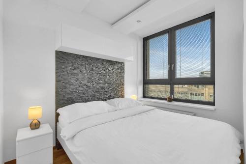 City Bright Apartment with Parking & Balcony في Trnávka: غرفة نوم بسرير ابيض وجدار من الطوب