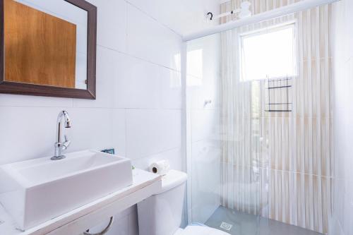 a white bathroom with a sink and a shower at Pousada In Bali - Maresias in Maresias