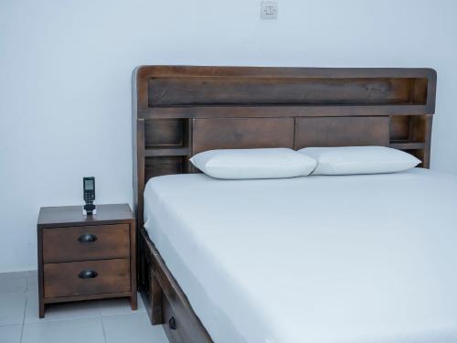 Appartement Cosy avec Balcon - Haie Vive في كوتونو: سرير مع اللوح الخشبي بجانب المنضدة