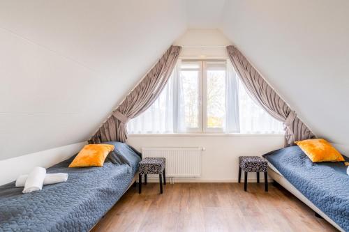 two beds in a attic bedroom with windows at Oude Dijkje in De Koog