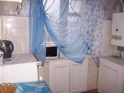 ヤロスラヴリにあるApartment Pisemskogo 46のキッチン(青いカーテン付きの窓付)