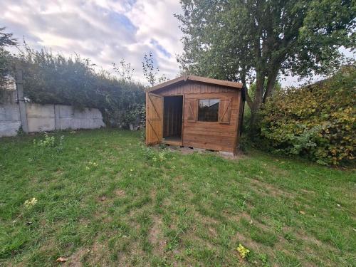 ein kleiner Holzschuppen auf einem Grasfeld in der Unterkunft Le Refuge des Dunes in Bray-Dunes