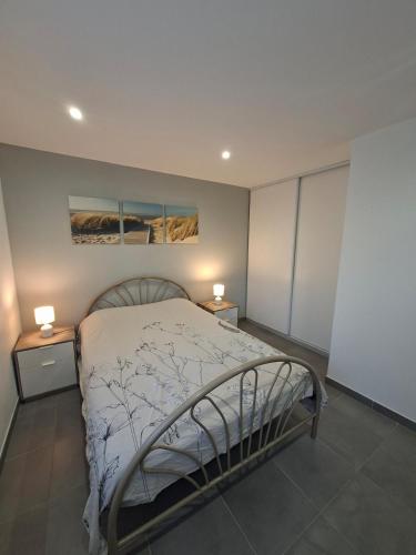 a bedroom with a bed with two night stands and two lamps at Le Refuge des Dunes in Bray-Dunes