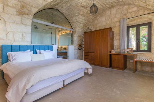 a bedroom with a large bed and a stone wall at Casa de Thoum in Batroûn