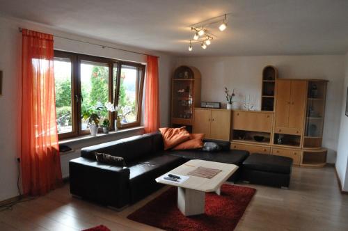 ein Wohnzimmer mit einem schwarzen Sofa und einem Tisch in der Unterkunft Ferienwohnung Blick in den Wasgau in Fischbach