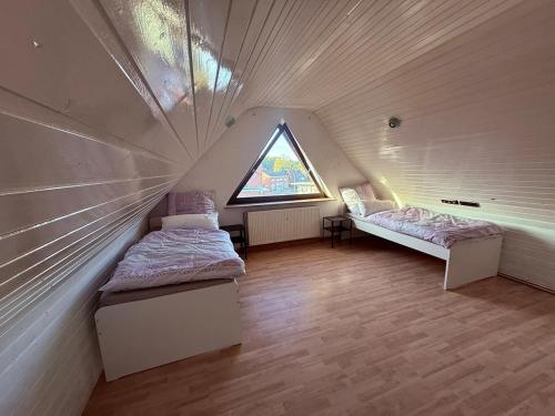 a attic room with two beds and a window at FeWo 5Z Terasse 2 Bad in Lingen