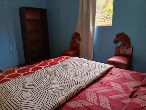 a bedroom with a bed and two red chairs at Hospedaje Tiyox Aab'aj in San Juan La Laguna
