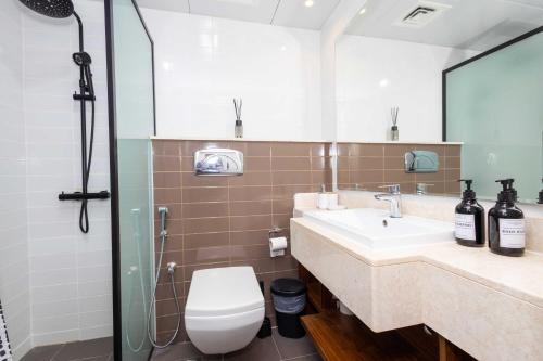 a bathroom with a toilet and a sink and a shower at Island Vista Haven 2 BR Private beach I Rooftop Pool in Ras al Khaimah