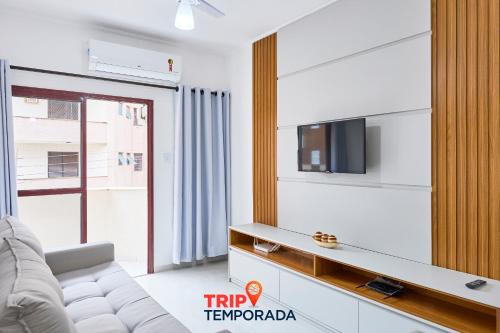 a living room with a couch and a tv at Apartamento espaçoso com ar condicionado e Wi-fi, a 100 metros da praia - Edifício Estoril in Ubatuba