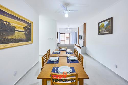 a dining room with a long wooden table and chairs at Apartamento espaçoso com ar condicionado e Wi-fi, a 100 metros da praia - Edifício Estoril in Ubatuba