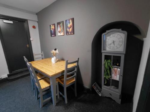 uma sala de jantar com uma mesa e um relógio em Allon Manor De'Grey em Hull