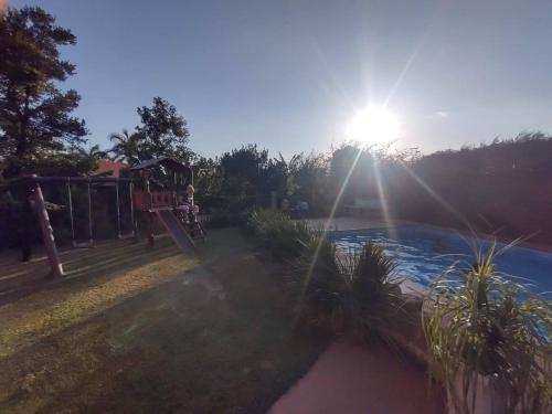 un parco con parco giochi con il sole sullo sfondo di Chácara Recanto Verde - Condomínio Vitassay- Boituva a Boituva