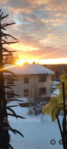 a building in the snow with the sunset in the background at Apartmán 254 b in Janske Lazne