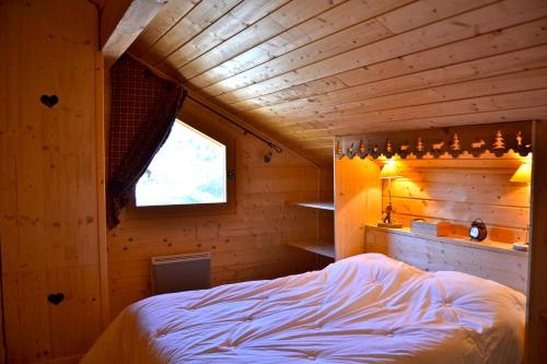 ラ・ジュー・デュ・ルーにあるChalet le Lagopèdeの木造キャビン内のベッド1台が備わるベッドルーム1室を利用します。