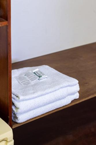 a stack of white towels on a wooden shelf at Pousada do Peralta in Bonito