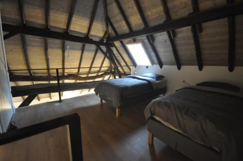 an attic bedroom with two beds and a window at Hoeve 't Peerdeke in Breda