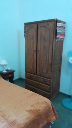 a bedroom with a wooden cabinet next to a bed at Vientoafavorcabanas in Chascomús