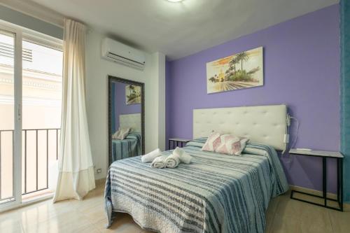 a purple bedroom with a bed with two stuffed animals on it at Duque Center Premium Suites in Seville