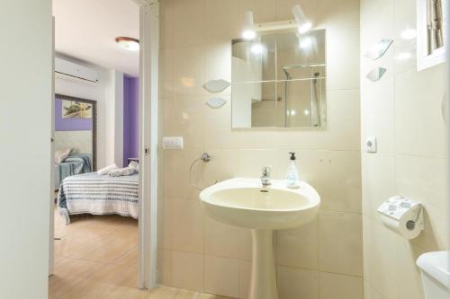 a white bathroom with a sink and a bedroom at Duque Center Premium Suites in Seville