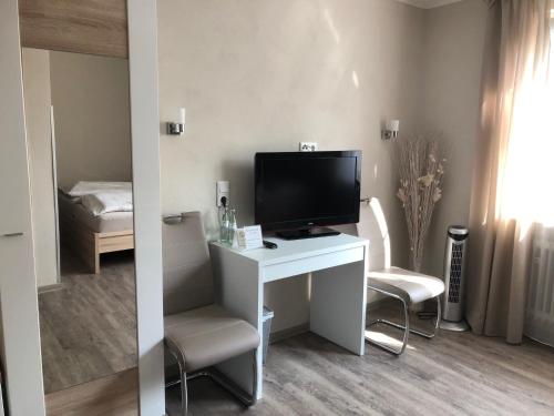 ein Zimmer mit einem Schreibtisch mit Fernseher und einem Bett in der Unterkunft Hotel Altstadt Wöllbacher Tor in Wetzlar