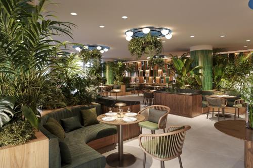 ein Restaurant mit Grünpflanzen, Tischen und Stühlen in der Unterkunft Royal Hideaway Casablanca in Casablanca