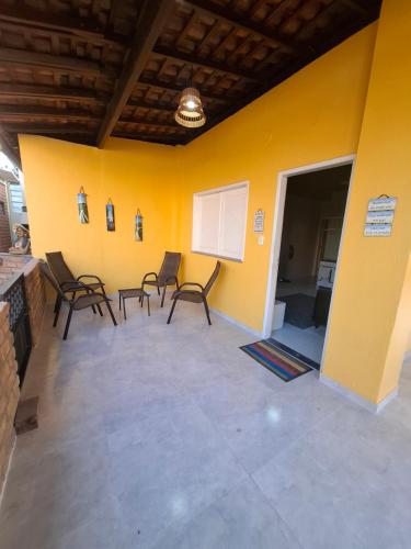 Zimmer mit Stühlen und gelber Wand in der Unterkunft Chalé Descanso - Cond Porto dos lençois Barreirinhas in Barreirinhas