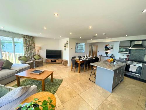 a kitchen and living room with a couch and a table at Trewhiddle Retreat V12 by Together Travel - Luxury 4-Bedroom Villa in St Austell