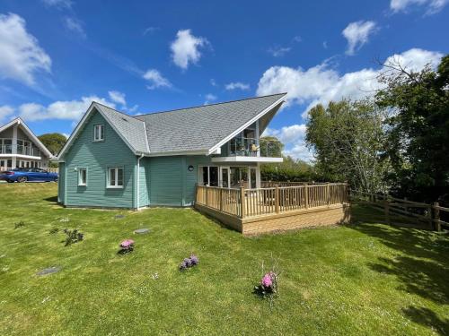 a blue house with a deck on a yard at Trewhiddle Retreat V12 by Together Travel - Luxury 4-Bedroom Villa in St Austell