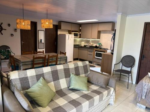 ein Wohnzimmer mit Couch und Küche in der Unterkunft Casa Piccolo Paradiso 4 quartos in Balneário Gaivotas