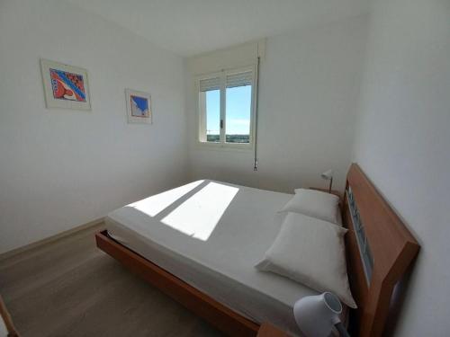 Un dormitorio con una cama grande y una ventana. en Residence Due Torri Tipo C, en Lignano Sabbiadoro