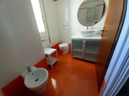 Un baño con lavabo, inodoro y espejo. en Residence Due Torri Tipo C, en Lignano Sabbiadoro