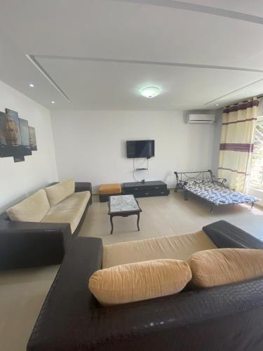 a living room with a couch and a tv at Rim Apartment , Beachfront in Ḩammām al Ghazzāz