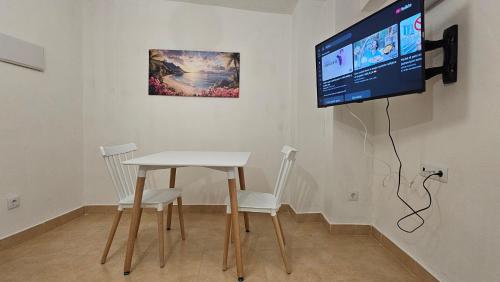 Una mesa blanca y sillas con un televisor en la pared. en Apartamento para pareja en Jaén, en Jaén