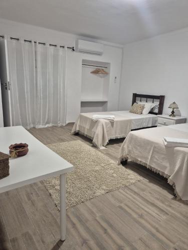 a white room with two beds and a table at Casa Branco in Borba