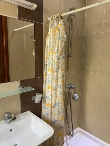 a bathroom with a shower curtain and a sink at Rim Apartment , Beachfront in Ḩammām al Ghazzāz