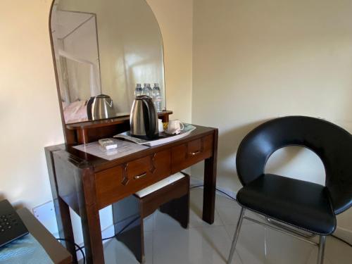 a desk with a chair and a mirror at The Palms Beach Hotel Tour Travel in Entebbe