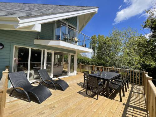 a deck with a table and chairs on a house at Trewhiddle Retreat V12 by Together Travel - Luxury 4-Bedroom Villa in St Austell
